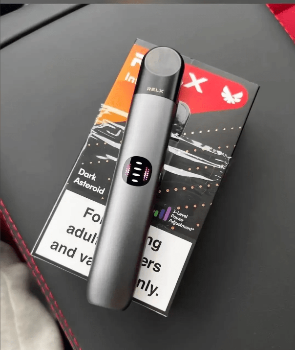 手持 RELX 悅刻六代霧化主機黑色款，呈現洗鍊工業設計與金屬質感